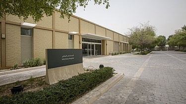 Eingangsbereich des Al Shaqab Equine Veterinary Medical Centre mit modernem Gebäudekomplex, Zufahrtsweg und Beschilderung der Veterinärklinik