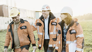 STRABAG Team Two men and a woman from the engineering team on a meadow