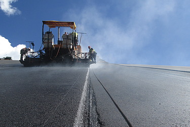 Einbau einer Asphaltoberfläche mit Spezialgerät auf einer großflächigen Infrastrukturbaustelle.