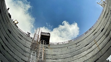 Upward view from a deep concrete shaft showing access ladders and an elevated work platform during construction of the DTSS link sewers