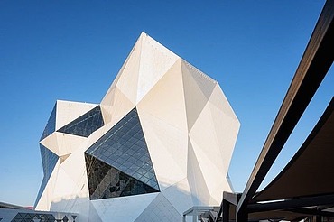 Futuristisches Gebäude der Sky-Venture-Anlage auf Yas Island mit weißer Fassade und großen Glasflächen, gespiegelt in einer Wasserfläche im Vordergrund