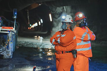 Personnel wearing protective equipment inside an underground tunnel at El Teniente Mine in Chile, with tunnel infrastructure and mining facilities visible in the background.