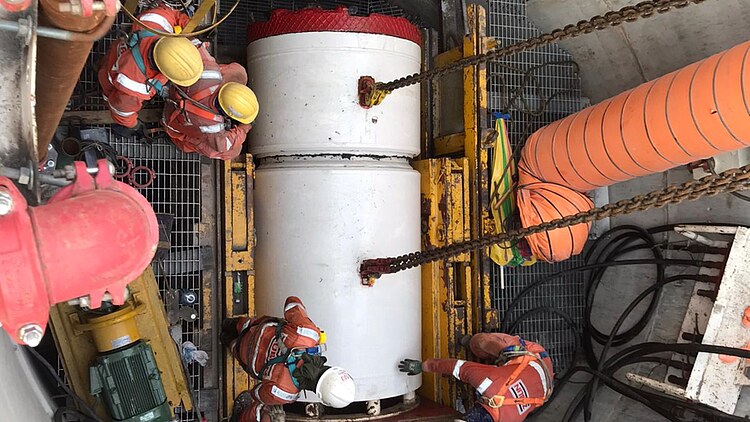A work crew lowers a large tunnel boring machine segment into a construction shaft for the CTSS Phase 2 Link Sewer Project